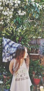 Young woman standing against plants