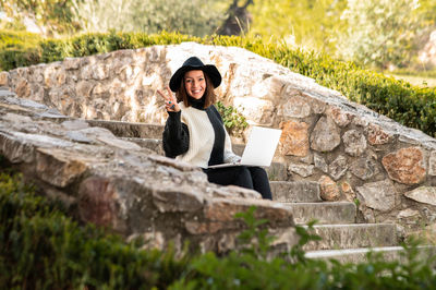 Woman making peace sign sitting on steps