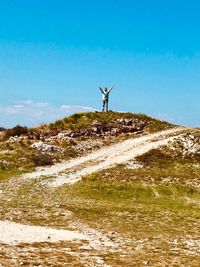 People standing on land by sea against blue sky