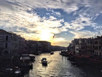 Boats in city against sky at sunset