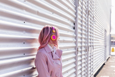 Woman with pink hair standing in front of metal wall