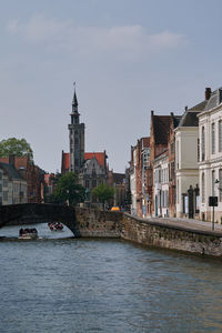 Buildings by river against sky, brugge, belgium