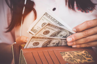 Midsection of woman removing paper currencies from purse