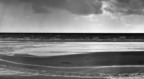 Scenic view of beach against cloudy sky