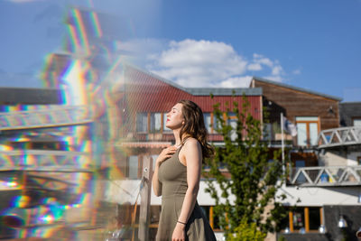 Double exposure of young woman and buildings during sunny day