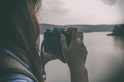 Rear view of woman photographing against sky