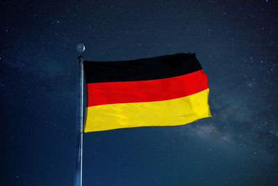 Low angle view of german flag against star field sky