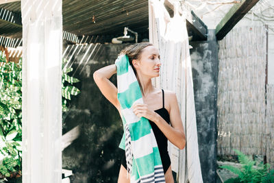 Portrait of young woman standing by window