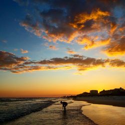 Silhouette people standing on beach against sky during sunset