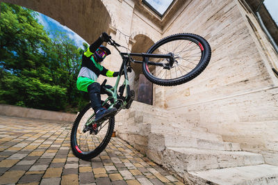 Active young biker jumping on the rear wheel of a mountain bike. extreme sport. wide angle front