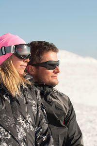 Smiling mid adult couple looking away on snowcapped mountain