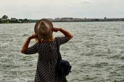 Rear view of woman standing by sea against sky