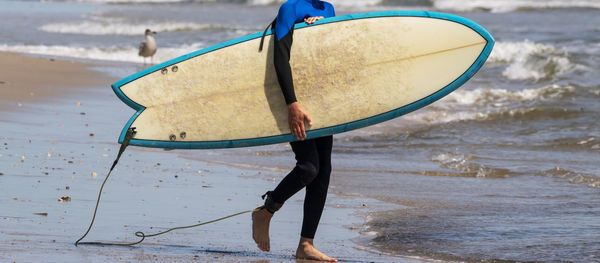 A man walking on the beach with a surfboard.