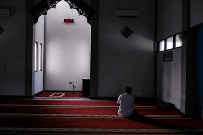 Rear view of man sitting in illuminated building