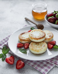 Cottage cheese pancakes, ricotta fritters on ceramic plate with fresh strawberry. 