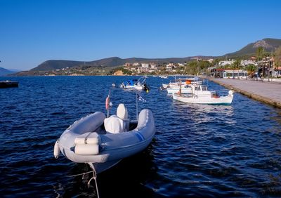 Boats moored in sea against clear blue sky