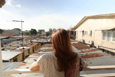 Rear view of woman with buildings against sky