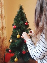Side view of girl decorating christmas tree at home