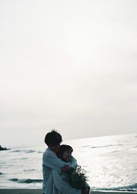 Rear view of couple on beach against sky