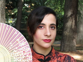 Close-up portrait of young woman with hand fan