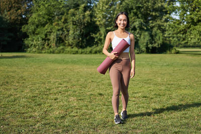 Full length of woman exercising on field