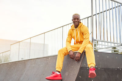 Portrait of man sitting by railing against sky