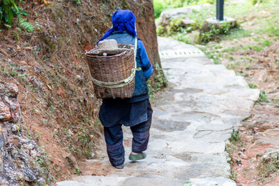 Rear view of man carrying basket while moving down on steps