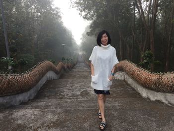 Portrait of smiling young woman standing against trees