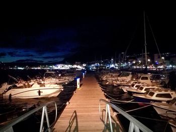 Boats moored at harbor against sky at night