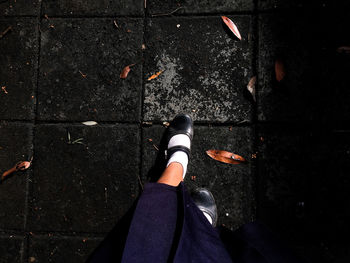 Low section of woman standing on footpath