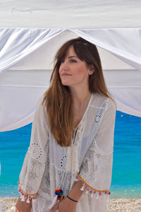 Beautiful young woman standing by sea