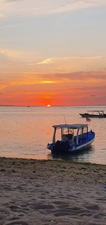 Boat moored on sea against sky during sunset