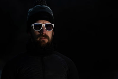 Portrait of man wearing sunglasses against black background
