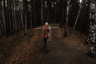 Young woman standing amidst trees in forest