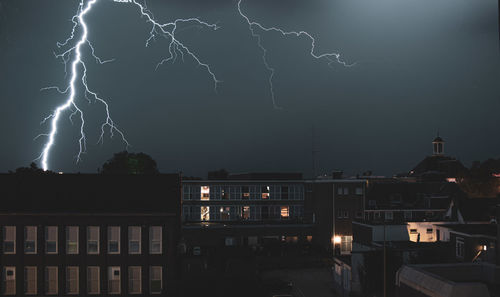 Lightning in city against sky at night