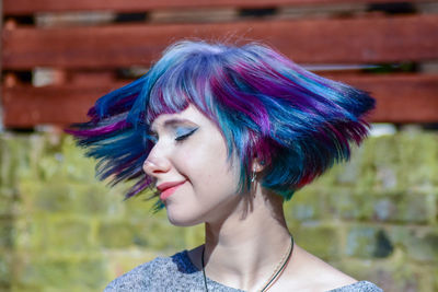 Hipster woman tossing colorful dyed hair outdoors