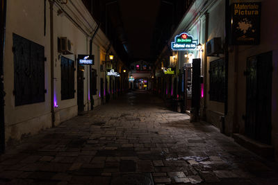 Empty alley amidst buildings in city at night