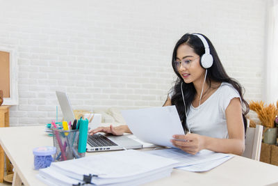 Young woman using mobile phone while sitting on table