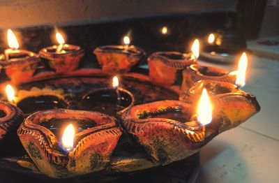 Close-up of illuminated diyas on plate