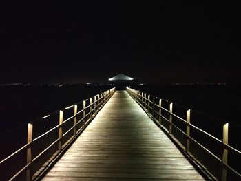 Footbridge over sea against clear sky at night