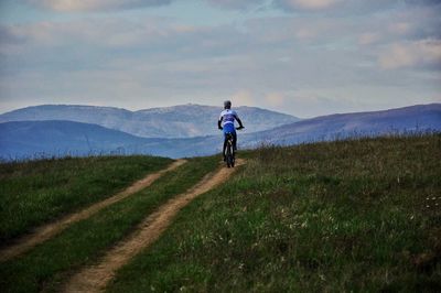 Man riding bicycle on mountain against sky