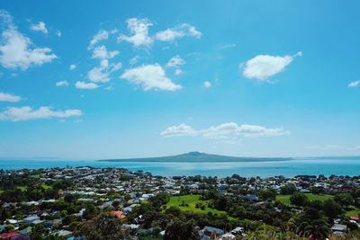 Aerial view of city by sea against blue sky