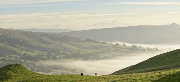 Scenic view of landscape against sky at sunrise with mist in valley