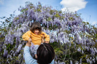 Mother holds daughter in yellow clothes in her arms