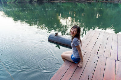 High angle view of smiling girl sitting on lake