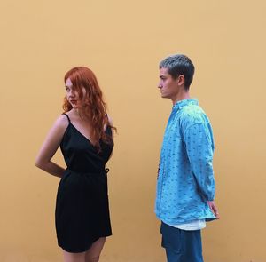 Young woman looking away against wall