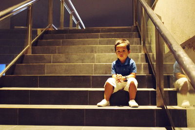Portrait of boy sitting on staircase