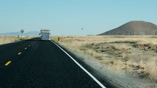 Road by mountain against clear blue sky