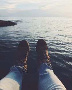 Low section of man sitting at beach during sunset