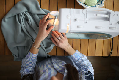 Caucasian girl with long dark hair sews on a sewing machine. 